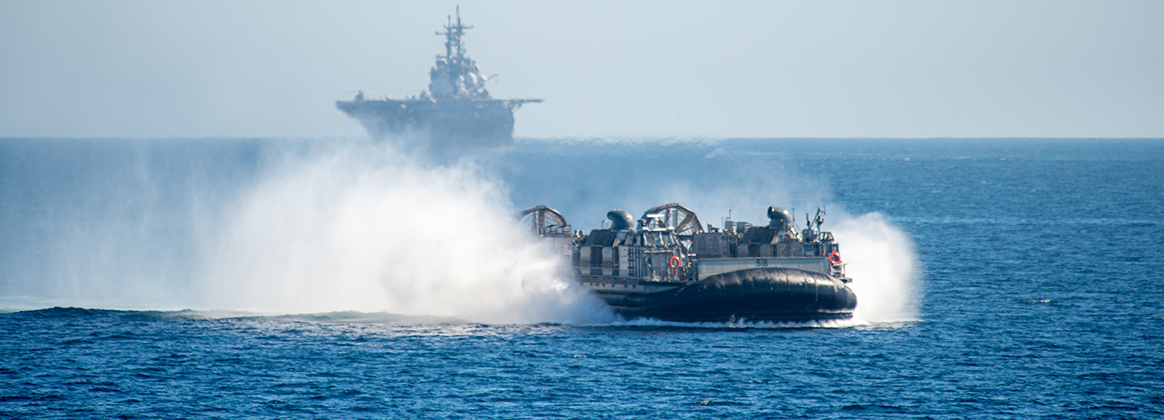 PACIFIC OCEAN (Nov. 5, 2023) A landing craft, air cushion assigned to Assault Craft Unit (ACU) 5 from the amphibious assault ship USS Boxer (LHD 4), background, transits the Pacific Ocean, Nov. 5, 2023. 